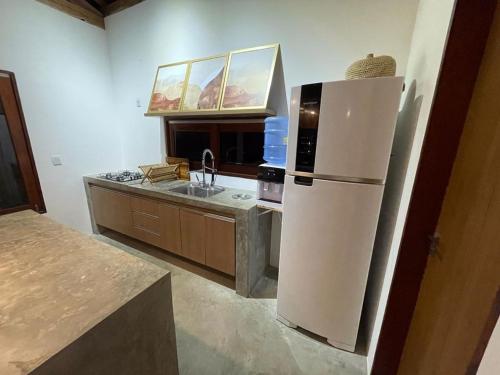 La cuisine est équipée d'un réfrigérateur blanc et d'un évier. dans l'établissement Casa Charme na Praia do Patacho-AL (prox.Milagres), à Porto de Pedras