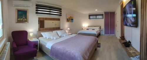 una habitación de hotel con 2 camas y una silla morada en Deluxe Villa Coast River Sarajevo, en Visoko