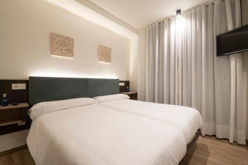 a bedroom with a white bed and a large window at Hotel A Mares in Celorio