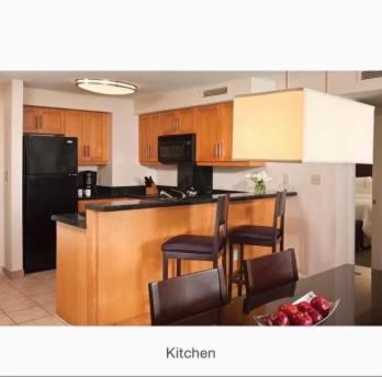 a kitchen with wooden cabinets and a black refrigerator at Westin St. John in Cruz Bay