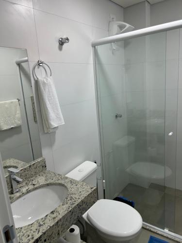 a bathroom with a shower and a toilet and a sink at Condomínio Kaimã in Matinhos