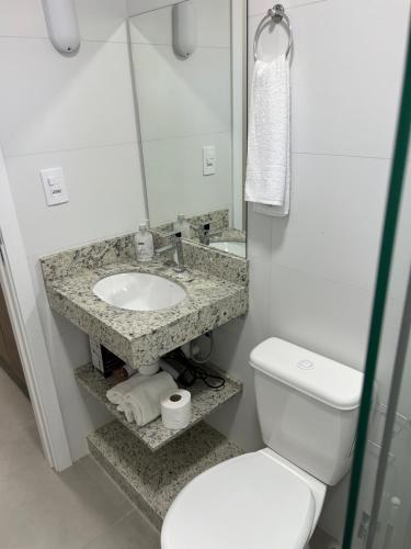 a bathroom with a sink and a toilet and a mirror at Condomínio Kaimã in Matinhos