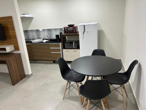 a kitchen with a table and black chairs at Condomínio Kaimã in Matinhos