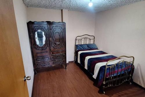 1 dormitorio con 1 cama y armario de madera en Casa y mirador, en Otavalo
