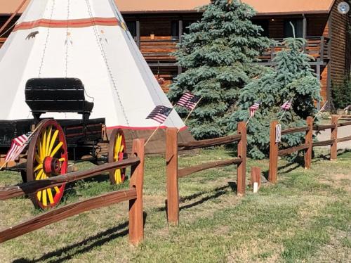 a wooden fence with a wagon in front of a christmas tree at Ute Bluff Lodge, Cabins and RV park in South Fork