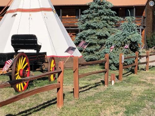 ein Holzzaun mit einem Wagen vor einem Weihnachtsbaum in der Unterkunft Ute Bluff Lodge, Cabins and RV park in South Fork