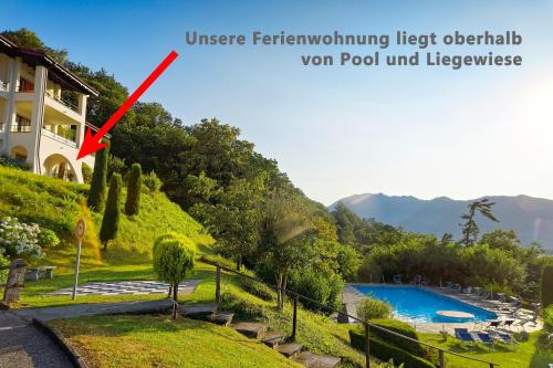 une flèche rouge indique une piscine dans un complexe dans l'établissement TOP-Ferienwohnung im Landhausstil mit Panoramablick & Pool, à Vira