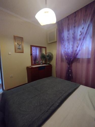 a bedroom with a bed with a purple curtain at Stella's Apartment in Áyios Pávlos