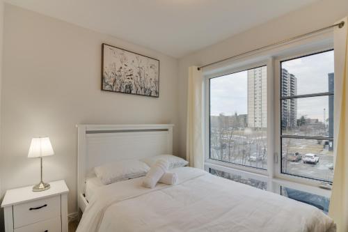 a white bedroom with a bed and a large window at Brand new townhouse, 30 minutes to Downtown in Toronto