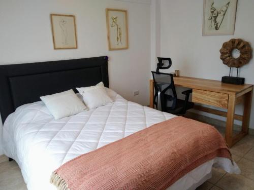 1 dormitorio con 1 cama blanca, escritorio y silla en Avenida Premium: Confort y Vistas Excepcionales en San Salvador de Jujuy