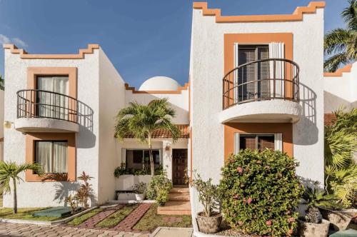 a white house with balconies and palm trees at Amazing Villas at Las Cupulas in Cancún