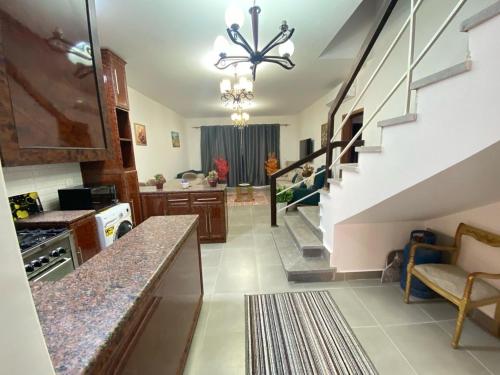 a kitchen with a staircase and a living room at قريه امواج بالساحل الشمالي شاليه دوبلكس فاخر in Sīdī ‘Abd ar Raḩmān
