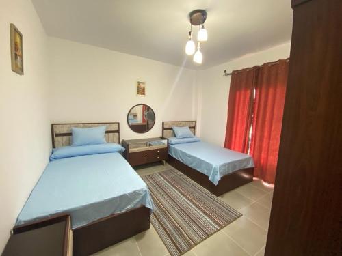a bedroom with two beds and a red curtain at قريه امواج بالساحل الشمالي شاليه دوبلكس فاخر in Sīdī ‘Abd ar Raḩmān
