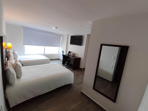 a hotel room with two beds and a mirror at Ramada by Wyndham Tampico Centro in Tampico