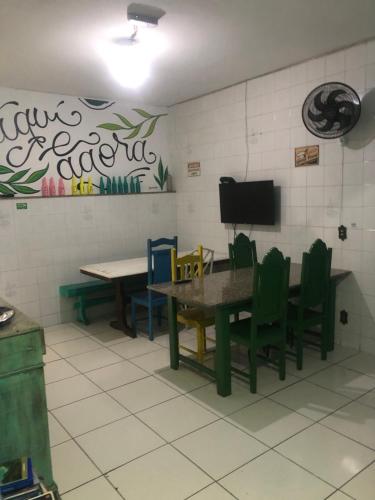 Habitación con mesa, sillas y TV. en Onça da Praia Hostel en Vitória