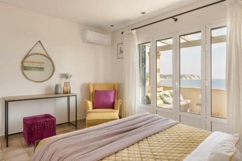 a bedroom with a bed and a chair and a window at Villa Eternity, Ai Helis Kefalonia in Kefallonia