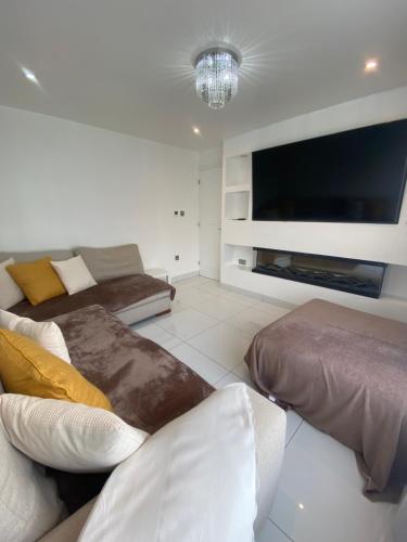 a living room with a couch and a flat screen tv at 3 Bedroom House in Northampton