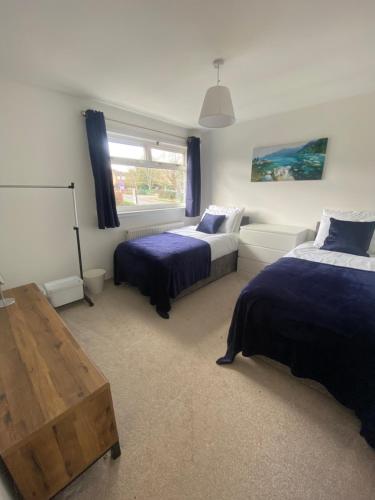 a bedroom with two beds and a table and a window at 3 Bedroom House in Northampton