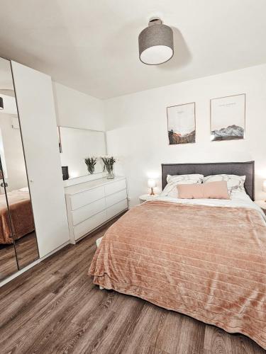 a white bedroom with a bed and a large mirror at Modernes Appartment im Grünen in Witten
