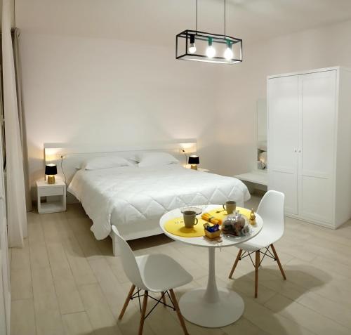 1 dormitorio con 1 cama, mesa y sillas en mya luxury rooms and wellness, en Melendugno