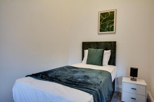 a bedroom with a bed with white sheets and a green pillow at Apartment In Wigan Free Secured Parking in Upholland