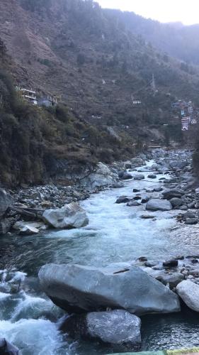 a river with rocks and a mountain in the background at Kasol Village Camp in Kasol