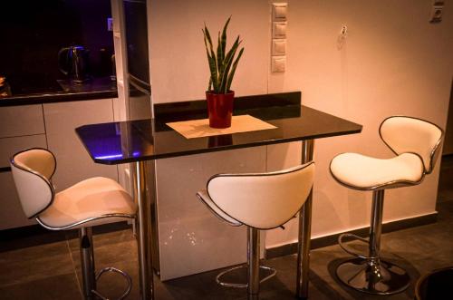 um balcão com três cadeiras e uma mesa com uma planta em Galaxyhome em Atenas