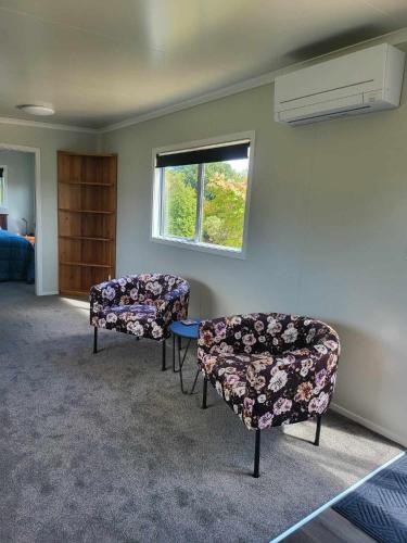 een kamer met 2 stoelen, een tafel en een raam bij Hillview in Waimate