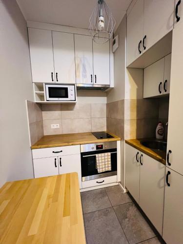 cocina con armarios blancos y fogones en Abra V Apartament en Poznan