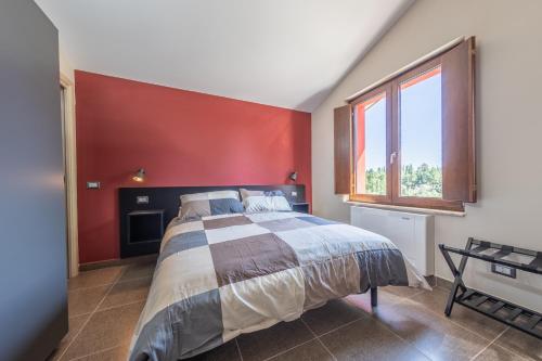- une chambre avec un lit et un mur rouge dans l'établissement Sanbarto la Casa del Borgo, 