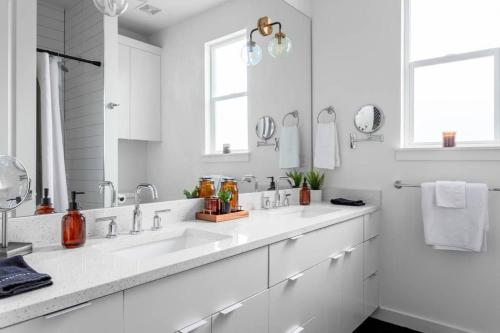 Baño blanco con lavabo y espejo en Insta-worthy - 6BR Home Rainey Street - 6 min walk en Austin