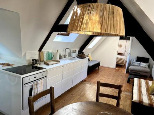 une cuisine avec des armoires blanches et une table dans une pièce dans l'établissement Charmant T4 entièrement rénové !, à Lannion