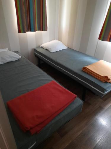 - 2 lits dans une petite chambre avec une couverture rouge dans l'établissement Mobil-home C007 - C008, à Boofzheim