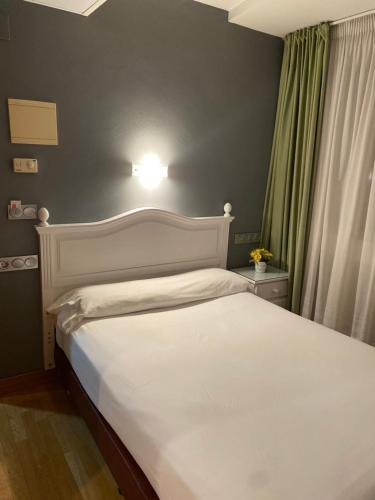 een slaapkamer met een bed met een witte sprei bij Hotel Villa De Ermua in Ermua