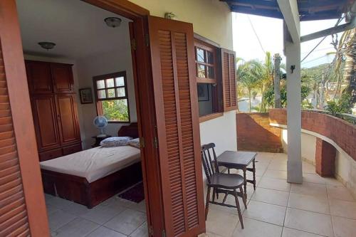 een slaapkamer met een bed en een balkon met een tafel en stoelen bij Espaço inteiro: casa Manguinhos/Geribá in Búzios