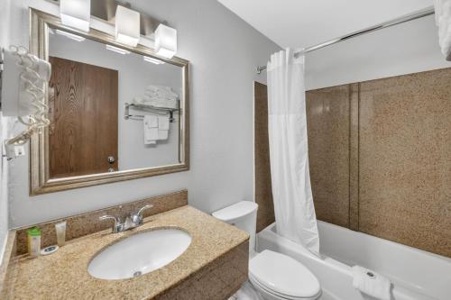 uma casa de banho com um lavatório, um WC e um espelho. em City Center Inn em Newport News