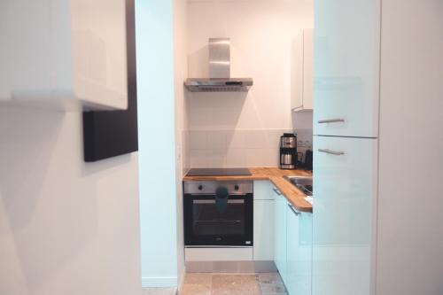 Il comprend une cuisine blanche équipée d'une cuisinière et d'un réfrigérateur. dans l'établissement Le Prévert, T3 en centre ville, à Tours