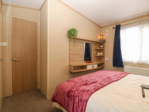 a bedroom with a large bed and a window at Seafront Holiday Home 2 in Pwllheli