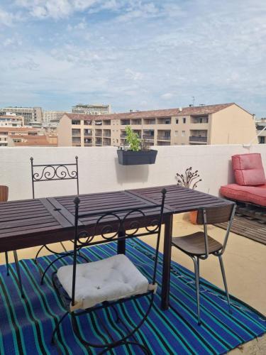 une table et des chaises en bois sur un balcon dans l'établissement Appartement Rooftop / Terrasse, à Marseille