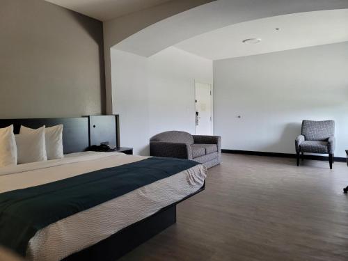 a hotel room with a bed and two chairs at Days Inn & Suites by Wyndham Gonzales TX in Gonzales