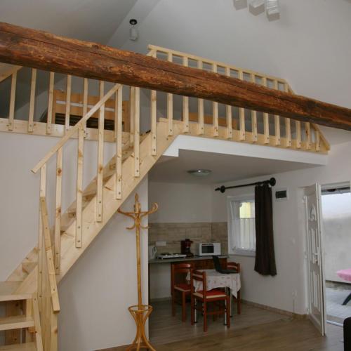 a wooden staircase in a living room with a kitchen at Biró Vendégház in Sármellék