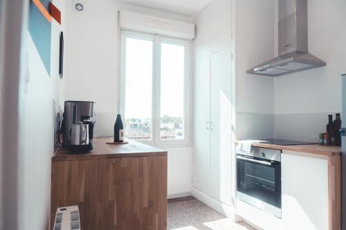 een keuken met witte muren, een raam en een fornuis bij Le Chenin T2 pour 4 personnes in Tours