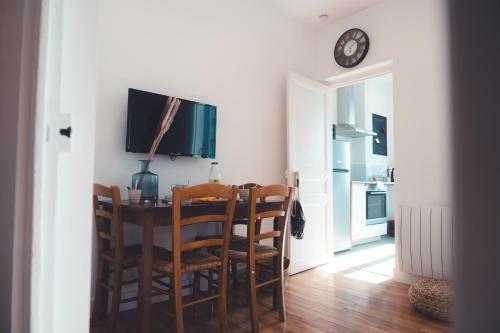 une salle à manger avec une table, des chaises et une horloge dans l'établissement Le Gamay Appartement 6 personnes, à Tours