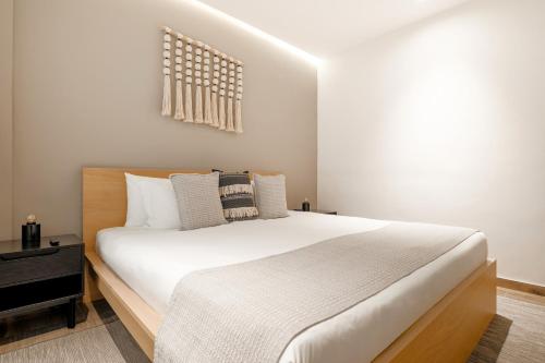 a bedroom with a large bed with white sheets at Lumina at Noma Condesa Mexico City in Mexico City