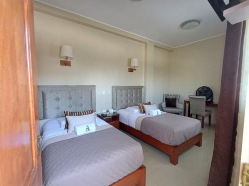 a hotel room with two beds and a chair at Arena Hostal in Paracas