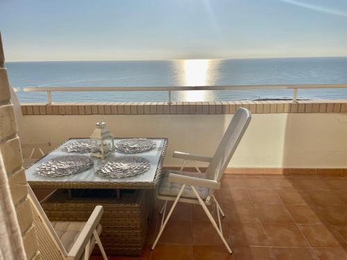 una mesa y sillas en un balcón con vistas al océano en Apartamento en primera linea frontal al mar, en El Borseral