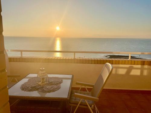 una mesa y sillas en un balcón con vistas al océano en Apartamento en primera linea frontal al mar, en El Borseral