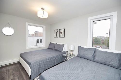 een slaapkamer met 2 bedden en 2 ramen bij Clifton Hill Hideaway 3B - Two Bedroom Condo in Niagara Falls