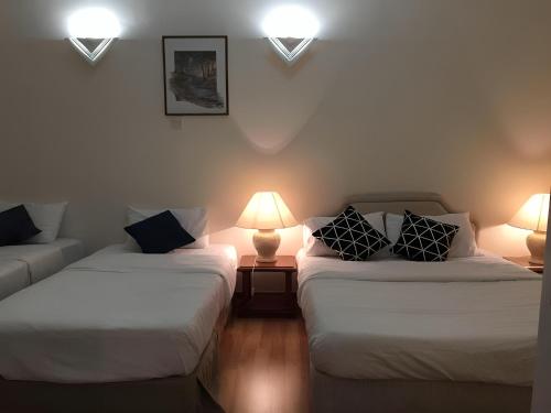 dwa łóżka w pokoju z dwoma lampami i kanapą w obiekcie Bukit Tinggi Fuchsia Hillhomes w mieście Bukit Tinggi