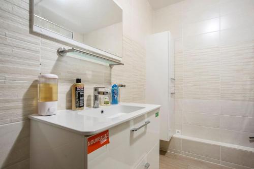 een badkamer met een witte wastafel en een douche bij Havre de paix : appartement de standing in Valenciennes